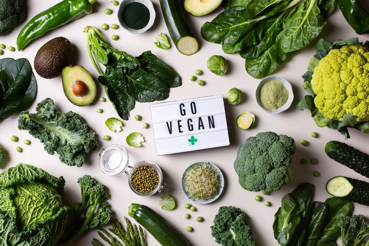 Tafel mit dem Schriftzug "Go vegan!" inmitten von verschiedenem grünem Gemüse